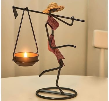Wrought iron tea light candle holder shaped like a person with a hat and scarf.